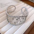Close-up detail of silver woven wire cuff bracelet with textured beads and open design. - Silver