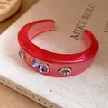 Macro view of pink resin open cuff bracelet featuring purple crystals in gold settings - Rose Red Pale Purple