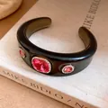 Close-up of black resin cuff bracelet with pink crystal rhinestones on a vintage book - Black Rose Red