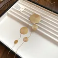 Vue détaillée d'un collier lasso doré avec des pendentifs circulaires en métal texturé - Or