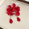 Close-up detail of bohemian matte red petal tassel earrings with elegant gold chains - Red