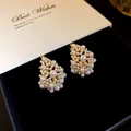 Close-up detail of elegant clustered pearl earrings on a premium black velvet jewelry box - Gold