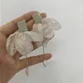 Détail de boucles d'oreilles vert sauge avec fleur en tissu blanc et goutte de perle - Nœud / Blanc