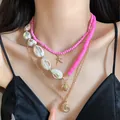 Close-up of pink layered beach necklace set with gold starfish and shell pendants - Three-Piece Set / Gold/White/Pink