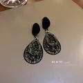 Detail showing black teardrop earrings with intricate filigree and crystal accents - Double Layer Water Drop Pave Style / Black