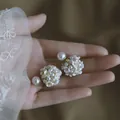 Elegant flower cluster pearl stud earrings with silver needles shown held in hand - Pearl Flower Cluster Style / White