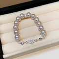 Detail view of elegant pearl bracelet with zircon flower charms on cream velvet display - Silver-Pink