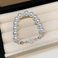 Close-up of elegant zircon flower pearl bracelet displayed in a cream jewelry box - Silver-White