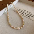Bohemian shell and pearl beaded necklace with gold accents on a textured background - Gold Khaki Shell