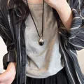 Close-up of a dual-tone oval pendant necklace on a minimalist black cord - 77# Necklace - Black