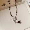 Detailed view of a silver-toned dachshund dog pendant with brown woven accents on a cord - 75# Dachshund / Silver-Coffee