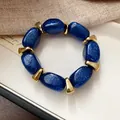Macro view of sparkly blue acrylic beads and gold spacers on a stylish bracelet. - Blue