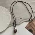 Detailed shot of a vintage acorn pendant necklace featuring a dark brown cord and resin stone - 78# Necklace - Brown