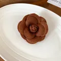 Detailed close-up of a brown flocking camellia flower brooch with soft felt texture finish - Brown