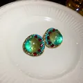 Close-up of vintage palace style earrings with green iridescent center and rhinestones. - 925 Silver Post Style / Gold
