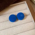Primer plano de pendientes redondos flocados azul real en un joyero de color crema elegante - Azul