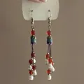 Close-up of bohemian tassel earrings with red beads and blue enamel flower caps - Hook Style / Gold Red Blue