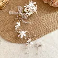 Macro view of Mori-style floral hair clip with white lace bow and long bead tassels - White