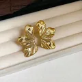 Vista detallada de elegantes pendientes dorados con textura de hoja en joyero - Dorado