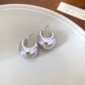 Vista detallada de pendientes de aro plateados en forma de C en plato blanco - Forma U/C Llena / Plateado