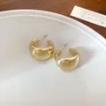 Elegantes pendientes geométricos dorados en forma de U sobre un plato de cerámica - Forma de U Retorcida Gruesa / Dorado