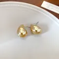 Primer plano detallado de pendientes de gota dorados pulidos en un plato de cerámica - Forma de gota de agua / Dorado