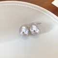 Primer plano de pendientes plateados con forma de gota en un plato de cerámica - Forma de gota de agua / Plateado