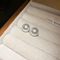 Primer plano de pendientes de botón de perlas blancas minimalistas en joyero vintage - 12mm / Blanco