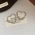 Macro view of minimalist silver heart-shaped hoop earrings with a polished finish - Large / Silver