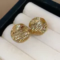 Detail view of 18k gold plated round stud earrings with unique wrinkled textured surface - Gold