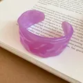 Dettaglio di un bracciale rigido vintage in acrilico viola con trama ondulata su un libro - Braccialetto N. 6 - Viola