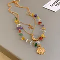 Detailed macro view of gold multi-layer necklace with sun, moon, star charms and stones. - Triple Layered Style / Gold