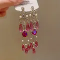 Vista dettagliata di orecchini vintage in stile palazzo con cristalli magenta e perle bianche - Oro