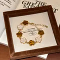 Detaillierte Nahaufnahme eines goldenen Vintage-Armbands mit emaillierten Blumenanhängern. - #27 Silberstift - Gold - Weiß - Braun - Sieben Blumen