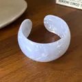 Primo piano di un bracciale rigido aperto in acrilico marmorizzato bianco - Bracciale 26# - Bianco
