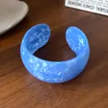Primo piano di un bracciale in acrilico blu retrò con trama marmorizzata su legno - 27# Bracciale Rigido-Blu