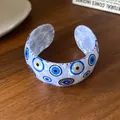 Dettaglio del bracciale rigido in acrilico bianco con motivo occhio di Allah blu. - Stile Aperto Malocchio (29#) / Bianco-Occhi