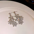 Detail view of vintage crystal flower drop earrings with hollow petals on white plate - Earrings / Silver