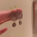 Detalle de pendientes elegantes con disco calado metálico y cuentas de color púrpura - Estilo de Gancho / Violeta Claro