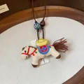 Detailed macro shot of an embroidered horse pendant necklace with wooden and resin beads. - Brown