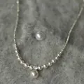 Detailopname van een elegante parelketting met zilveren kralen op zacht grijs imitatiebont. - 12# Ketting-Enkele Strass Parel / Zilver-Witte Parel