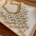 Detailed close-up of a vintage gold chain necklace with layered pearl fringe tassels - Gold White