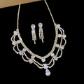 Close-up of a sparkling crystal water drop pendant jewelry set on black background - Necklace and Earrings / Gold