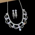 Close-up view of a luxury rhinestone teardrop jewelry set on black velvet background - Necklace and Earrings / Silver