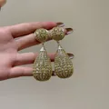 Vista dettagliata di grandi orecchini a goccia dorati con pavé di strass brillanti ed eleganti - Orecchini pendenti / Ago d'argento / Oro