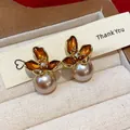 Detalle de pendientes vintage de flores en esmalte marrón y grandes perlas de color champán. - Estilo de Flor / Marrón