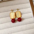 Close-up of vintage gold earrings with yellow cube and red glass bead pendants. - New Chinese Square Pendant Style (HE28054) / 925 Silver Post Style / Brown-Red