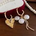 Detailed macro shot of vintage gold heart earrings with pearls and long rhinestone tassels - Gold