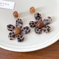Macro view of leopard print resin flower earrings with vintage brown center on ceramic plate - Dark Gold