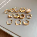 Detail view of 12 gold irregular geometric open rings set on a minimalist grey background. - Style 5